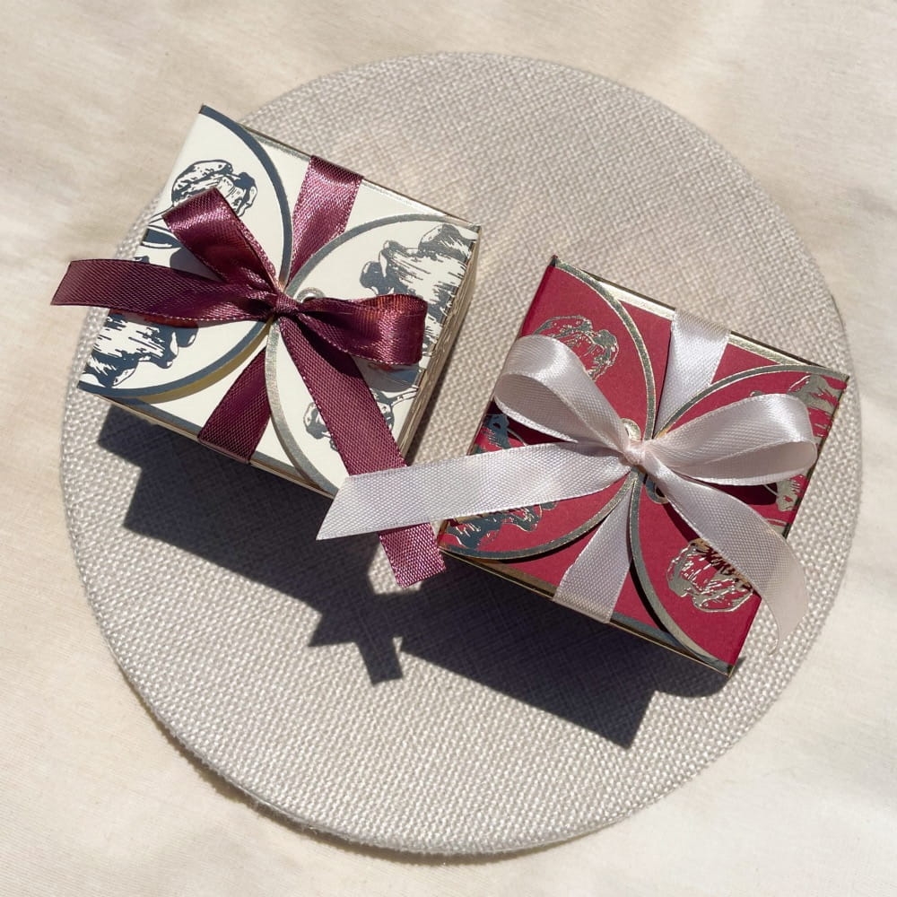 Upominek dla gości, drobny prezent w złoconym pudełku z kokardką. Do wyboru pudełko kremowe lub bordowe/burgundy. Wypełnienie, do wyboru: herbata sypana, herbata rozkwitająca, słodycze.