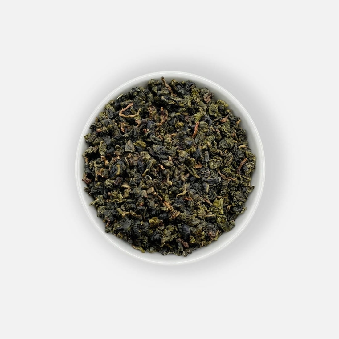 Herbata liściasta Milky Oolong o półfermentowanych liściach, podana w białej miseczce, ujęcie z góry.