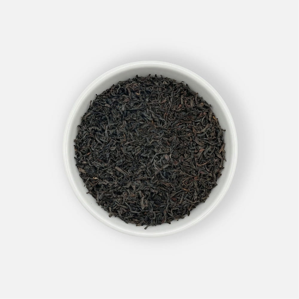Czarna herbata liściasta Ceylon FBOP o drobniejszych, łamanych liściach, podana w białej miseczce, ujęcie z góry.