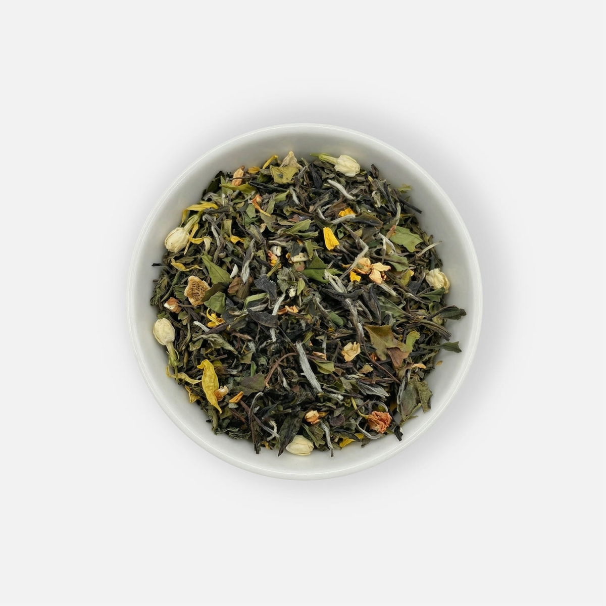 Biała herbata liściasta Daydreamer z Pai Mu Tan, kwiatem jaśminu, kawałkami mango i płatkami słonecznika, podana w białej miseczce, ujęcie z góry.