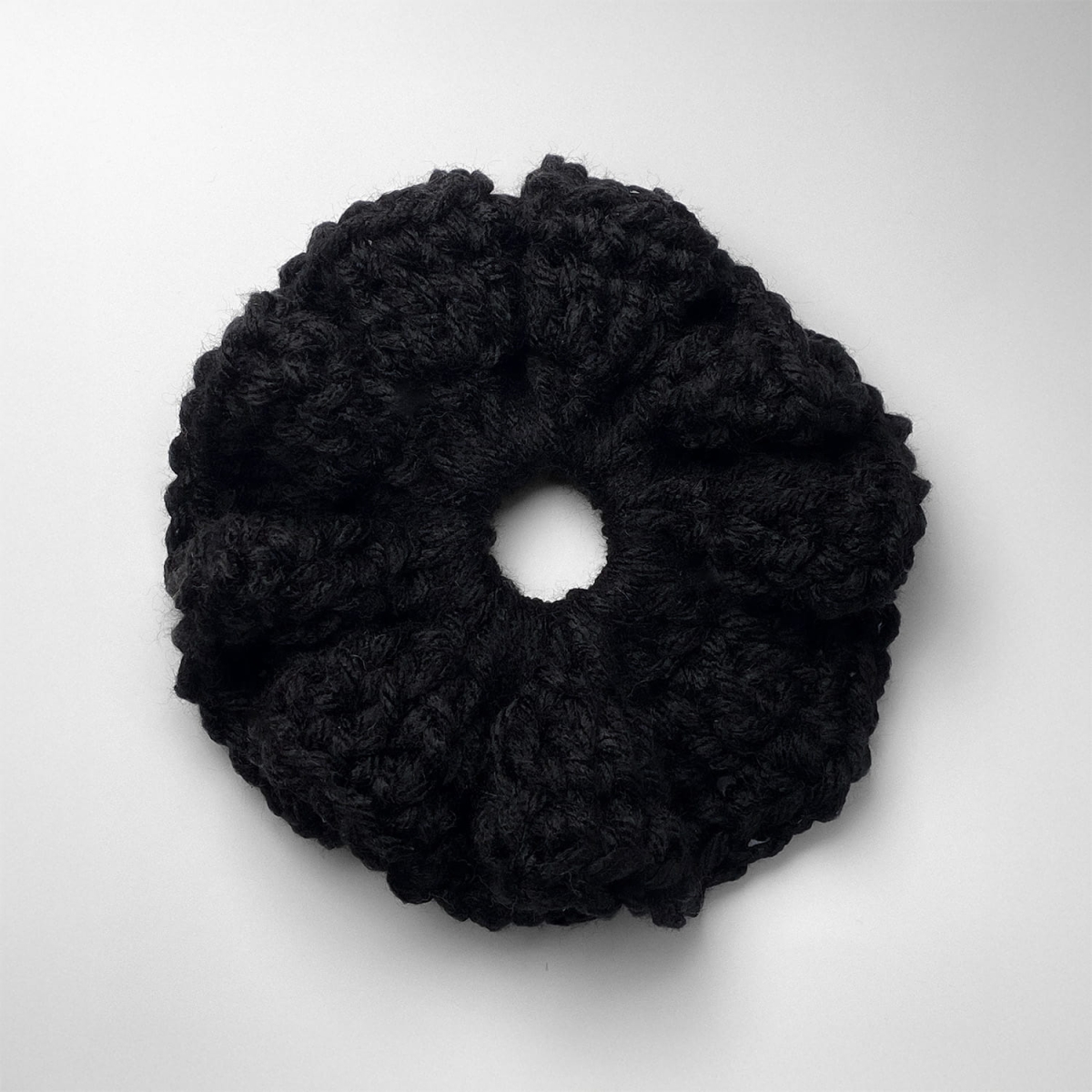 Ręcznie robiona gumka do włosów na szydełku wykonana z materiałów z upcyklingu, widok z góry na białym tle.