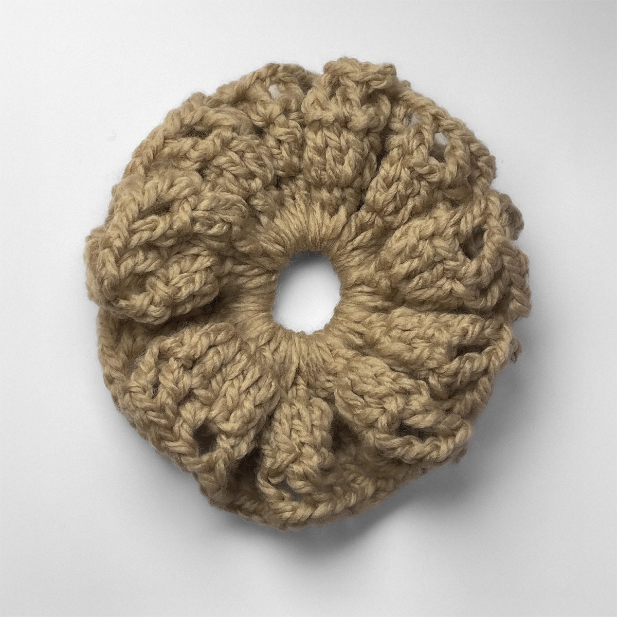 Ręcznie robiona gumka do włosów na szydełku wykonana z materiałów z upcyklingu, widok z góry na białym tle.