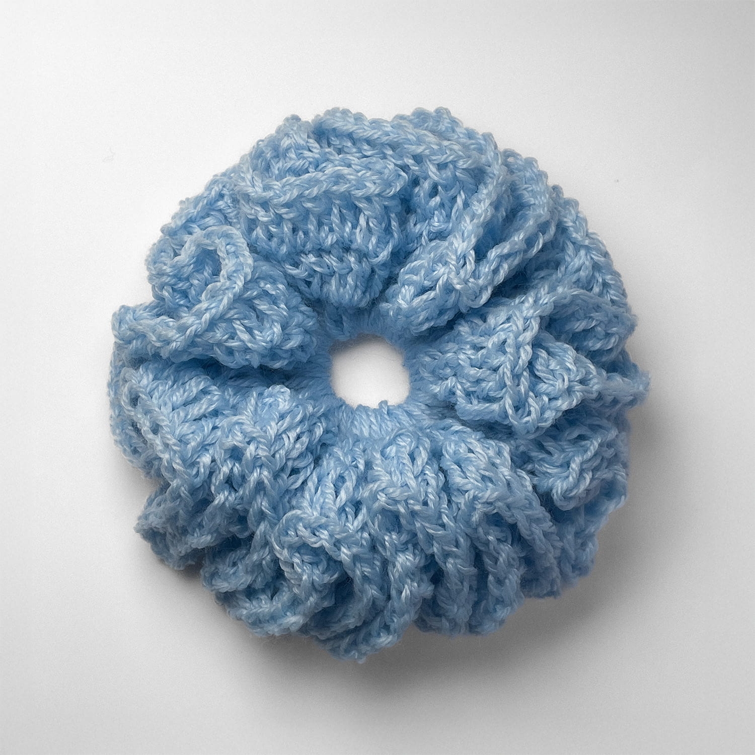 Ręcznie robiona gumka do włosów na szydełku wykonana z materiałów z upcyklingu, widok z góry na białym tle.