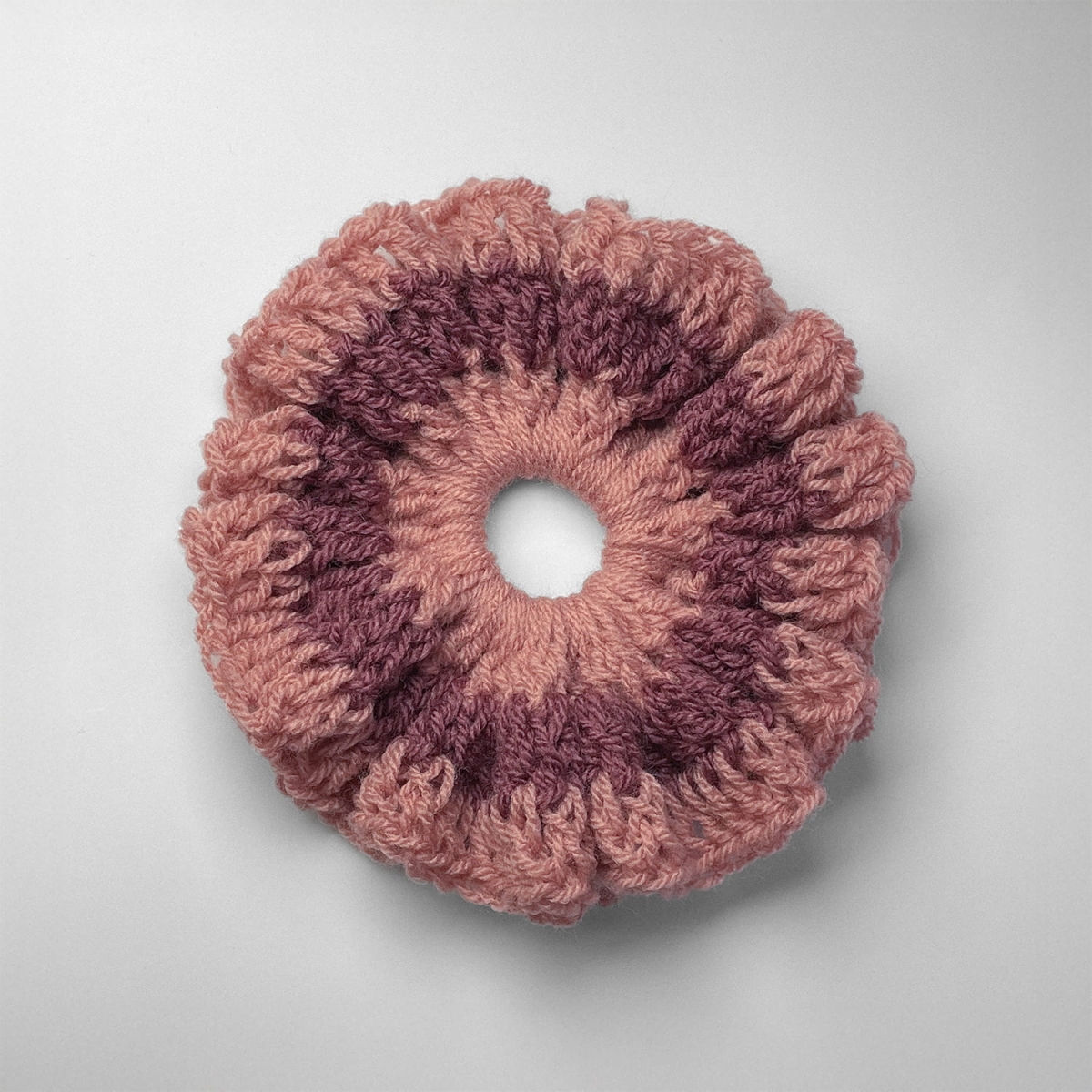 Ręcznie robiona gumka do włosów na szydełku wykonana z materiałów z upcyklingu, widok z góry na białym tle.