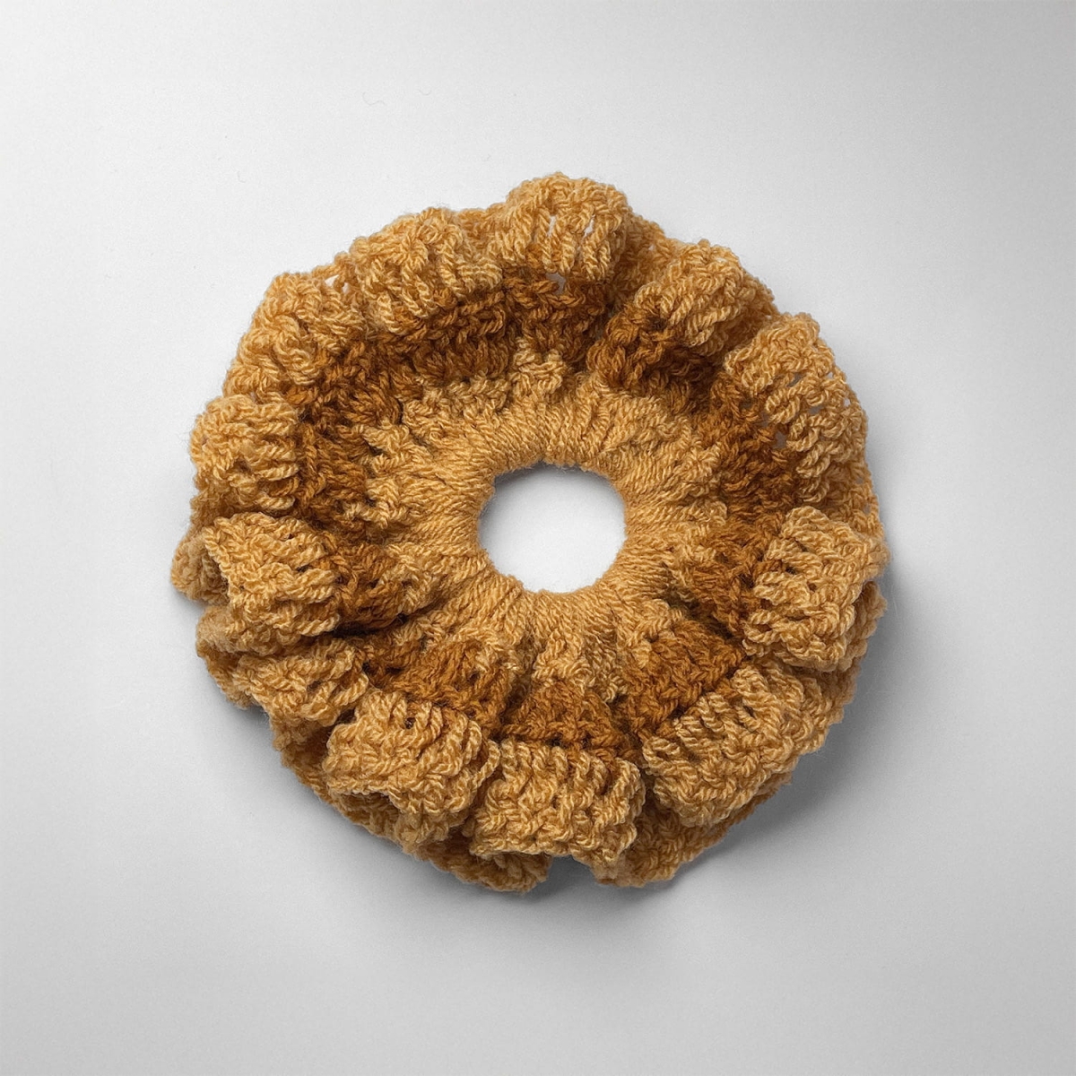 Ręcznie robiona gumka do włosów na szydełku wykonana z materiałów z upcyklingu, widok z góry na białym tle.