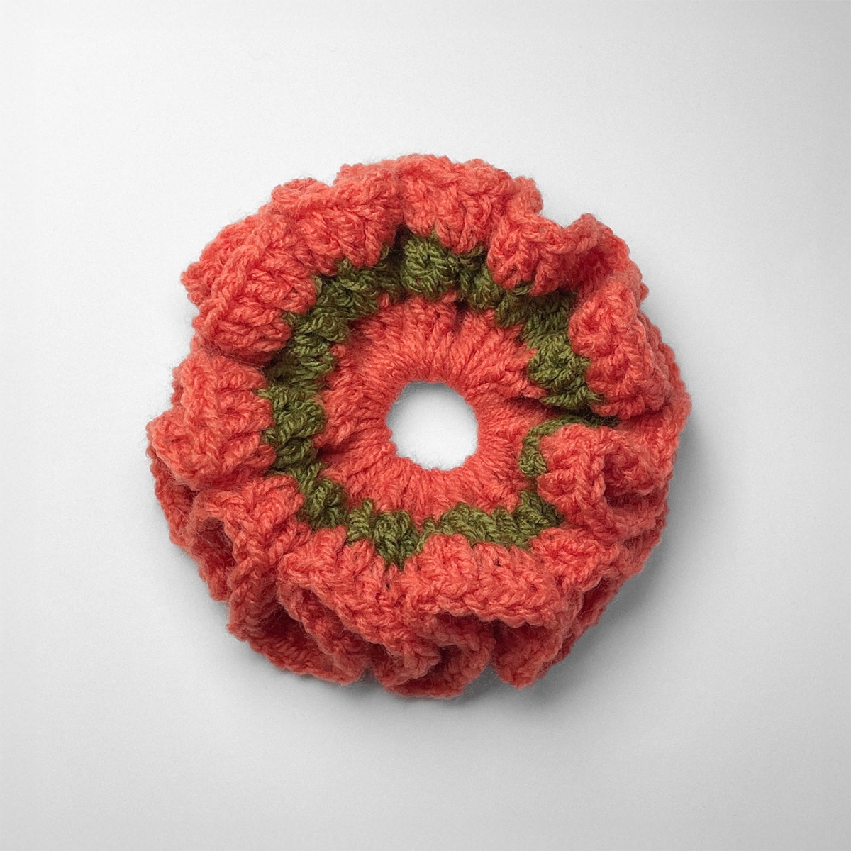 Ręcznie robiona gumka do włosów na szydełku wykonana z materiałów z upcyklingu, widok z góry na białym tle.