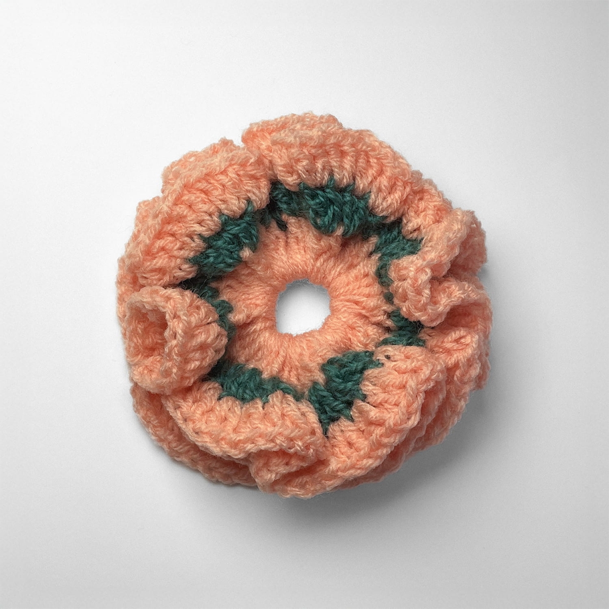 Ręcznie robiona gumka do włosów na szydełku wykonana z materiałów z upcyklingu, widok z góry na białym tle.