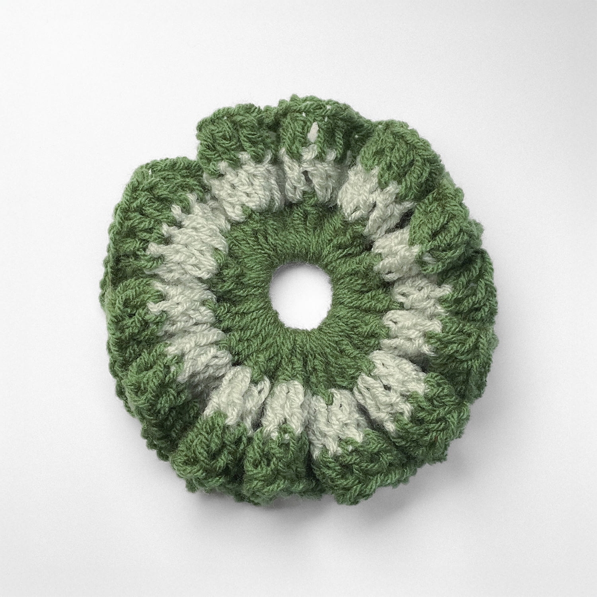 Ręcznie robiona gumka do włosów na szydełku wykonana z materiałów z upcyklingu, widok z góry na białym tle.