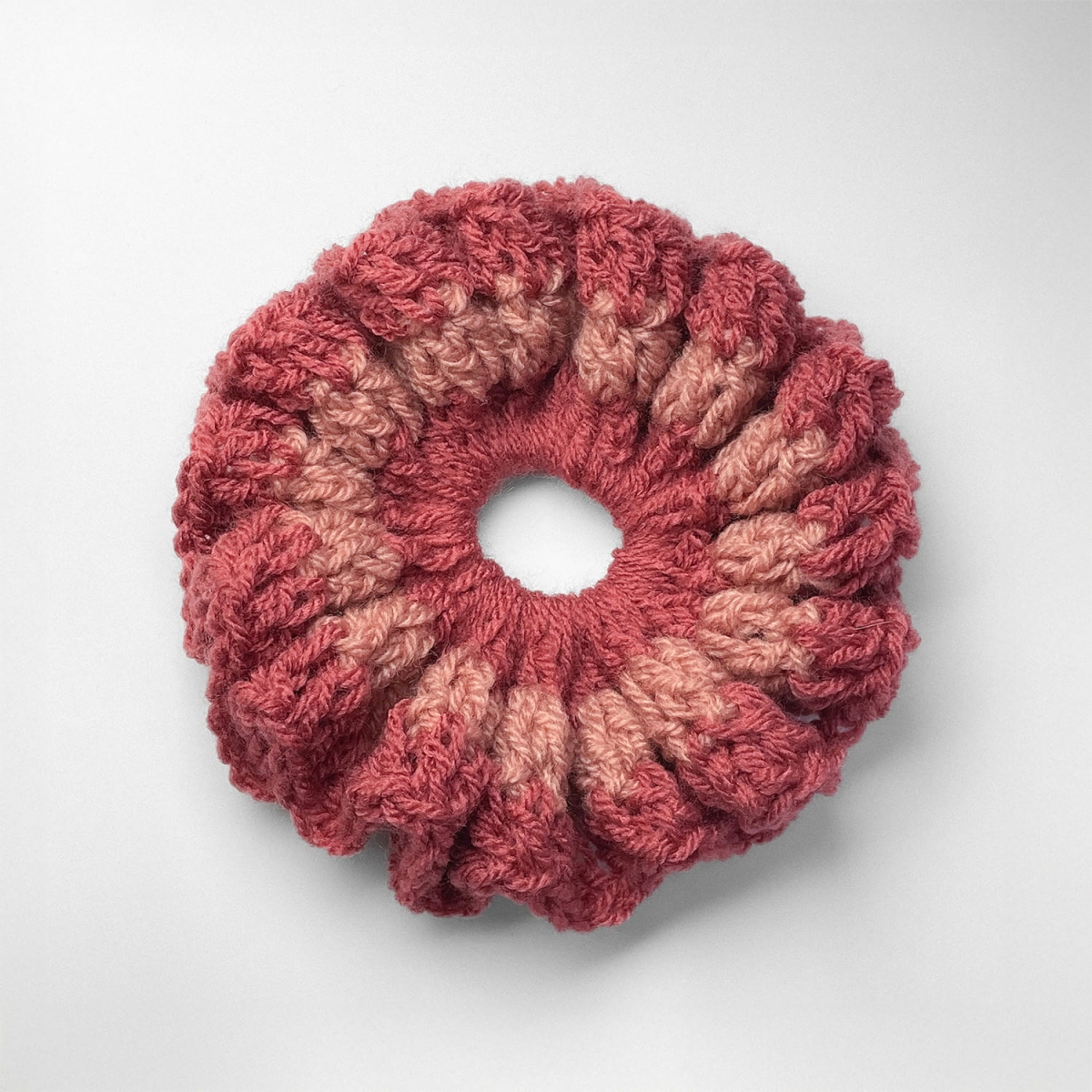 Ręcznie robiona gumka do włosów na szydełku wykonana z materiałów z upcyklingu, widok z góry na białym tle.