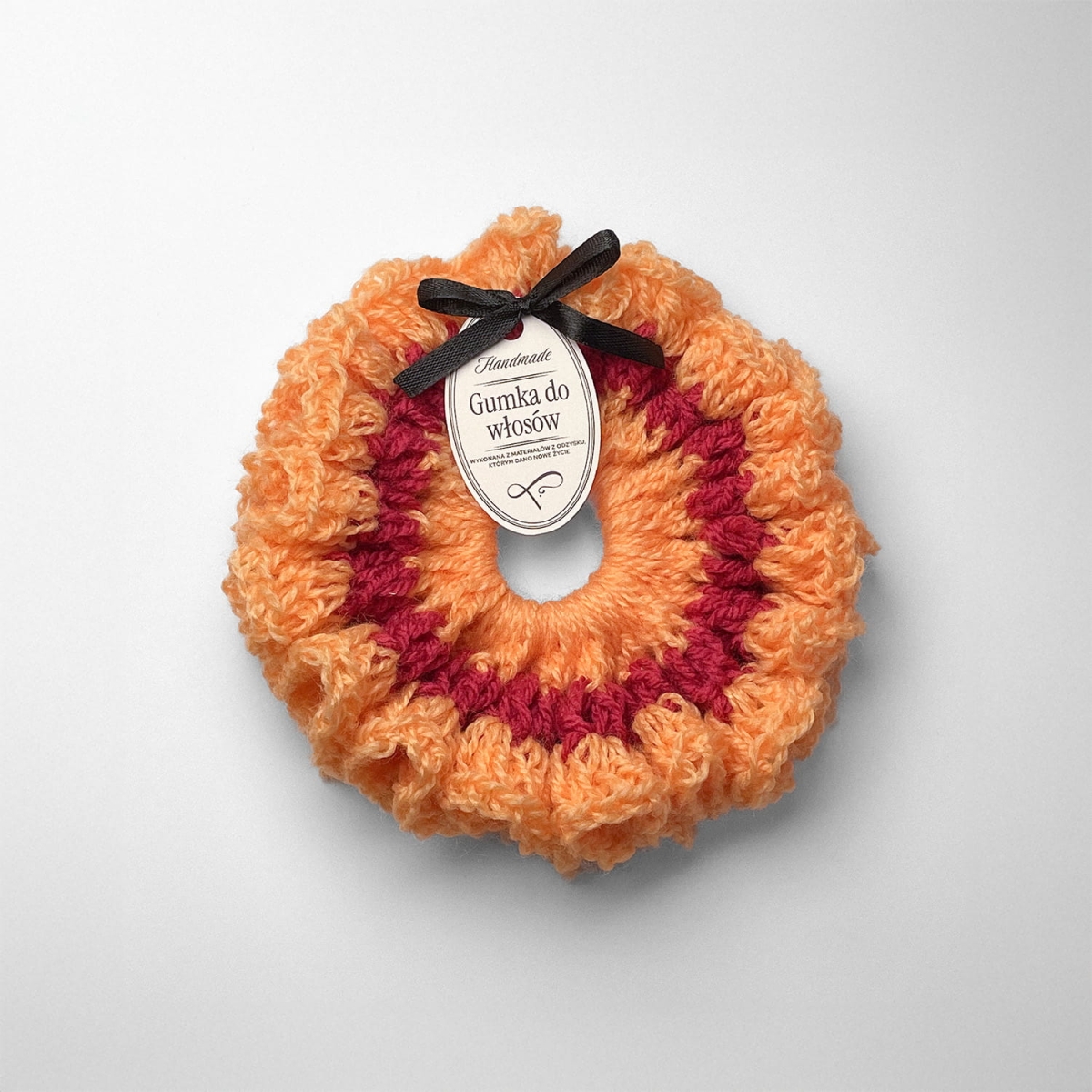 Ręcznie robiona gumka do włosów na szydełku wykonana z materiałów z upcyklingu, widok z góry na białym tle.