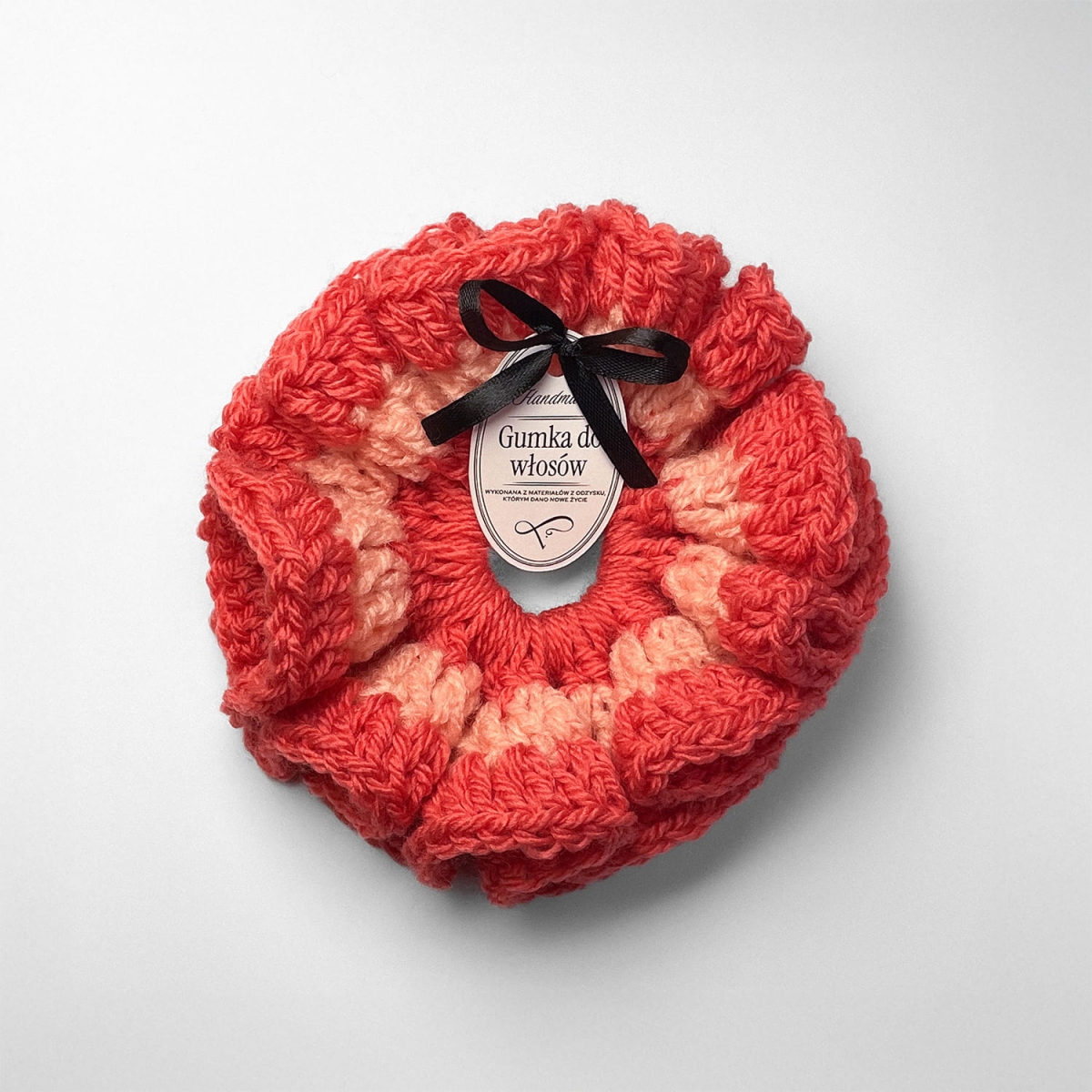 Ręcznie robiona gumka do włosów na szydełku wykonana z materiałów z upcyklingu, widok z góry na białym tle.