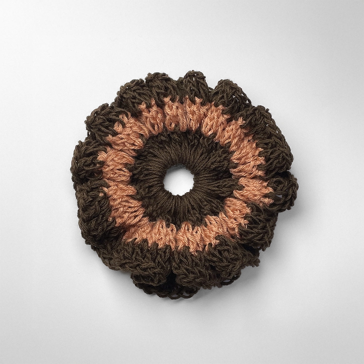 Ręcznie robiona gumka do włosów na szydełku wykonana z materiałów z upcyklingu, widok z góry na białym tle.