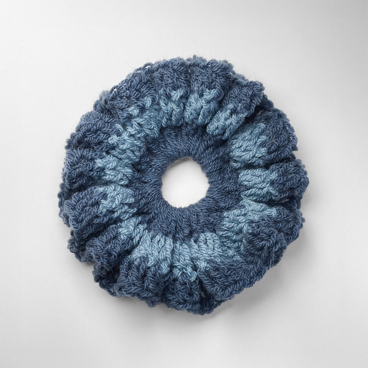 Ręcznie robiona gumka do włosów na szydełku wykonana z materiałów z upcyklingu, widok z góry na białym tle.