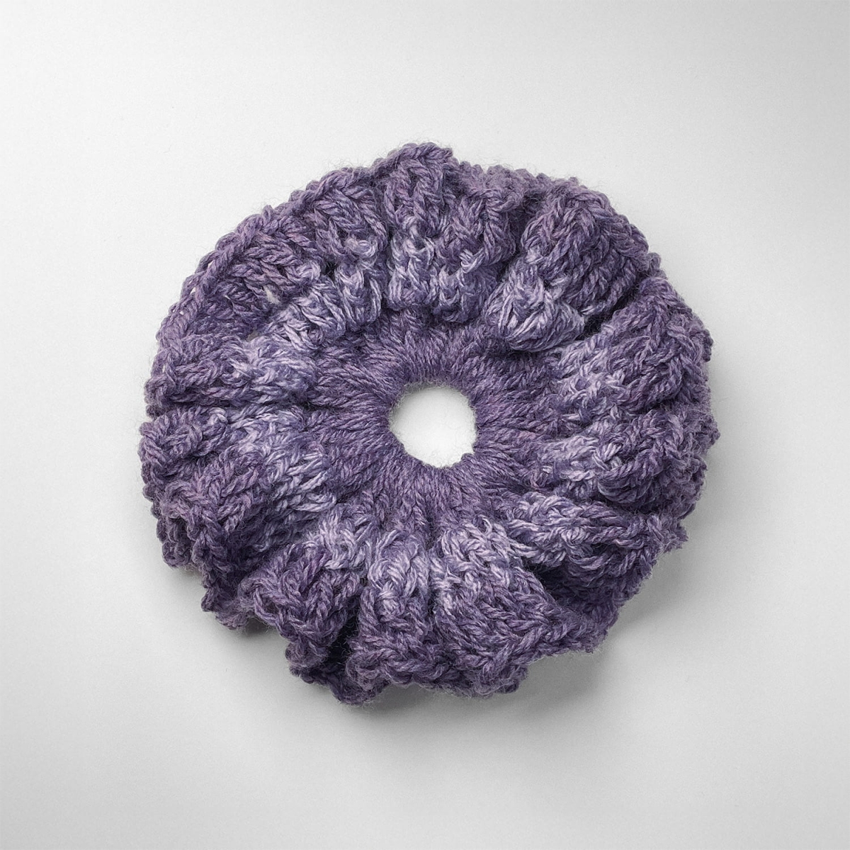Ręcznie robiona gumka do włosów na szydełku wykonana z materiałów z upcyklingu, widok z góry na białym tle.