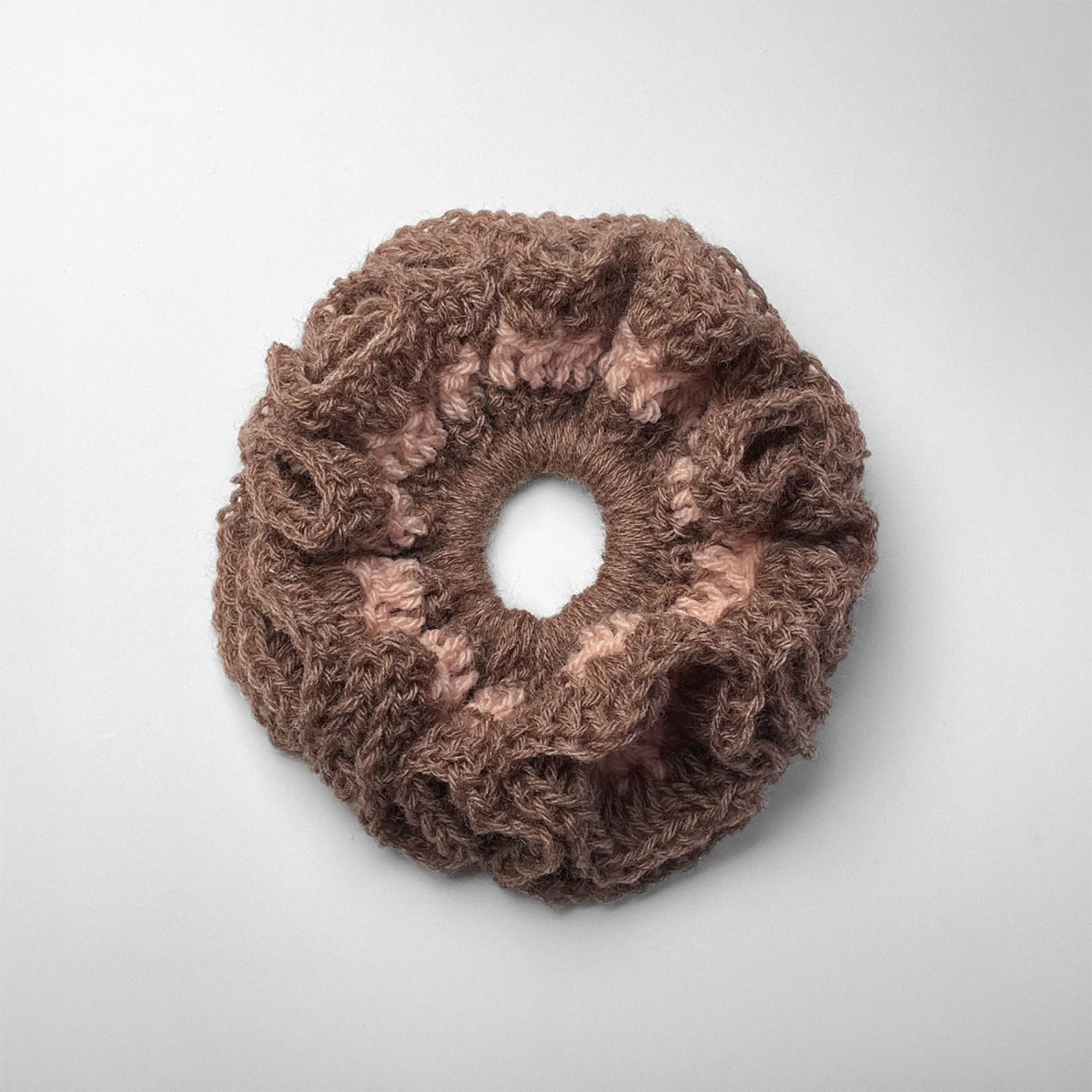 Ręcznie robiona gumka do włosów na szydełku wykonana z materiałów z upcyklingu, widok z góry na białym tle.