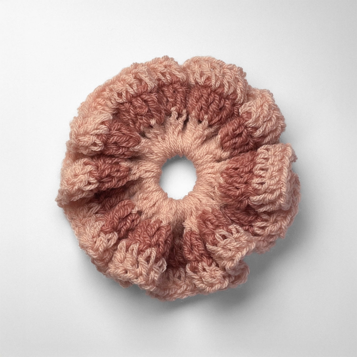 Ręcznie robiona gumka do włosów na szydełku wykonana z materiałów z upcyklingu, widok z góry na białym tle.