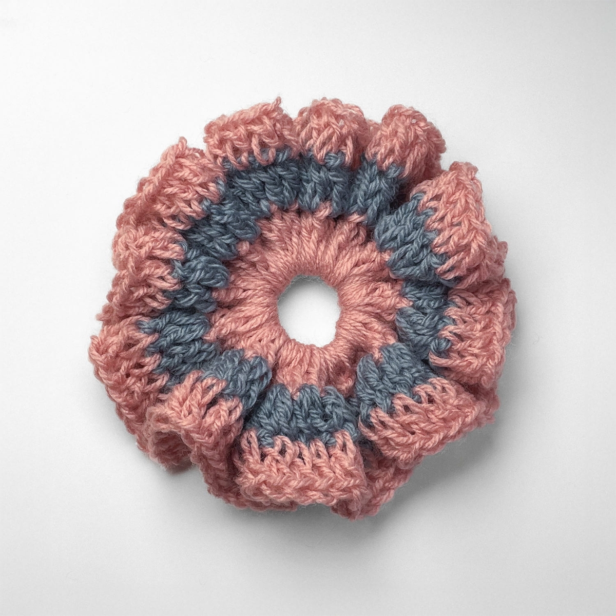 Ręcznie robiona gumka do włosów na szydełku wykonana z materiałów z upcyklingu, widok z góry na białym tle.