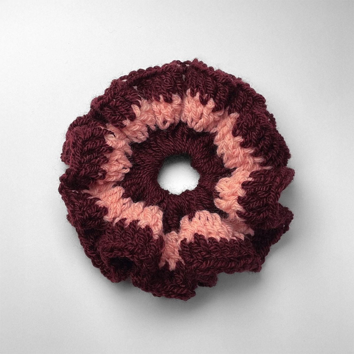 Ręcznie robiona gumka do włosów na szydełku wykonana z materiałów z upcyklingu, widok z góry na białym tle.