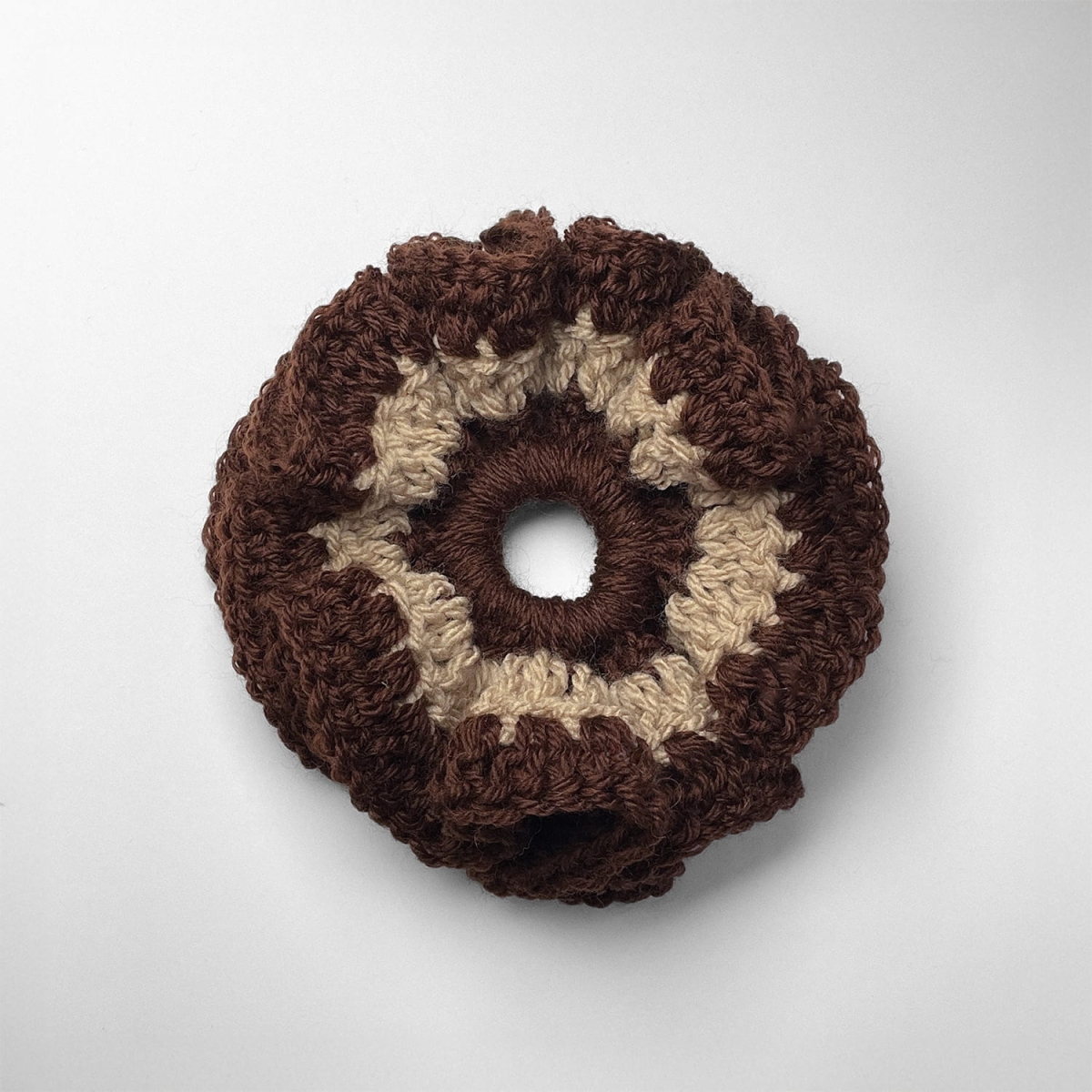 Ręcznie robiona gumka do włosów na szydełku wykonana z materiałów z upcyklingu, widok z góry na białym tle.