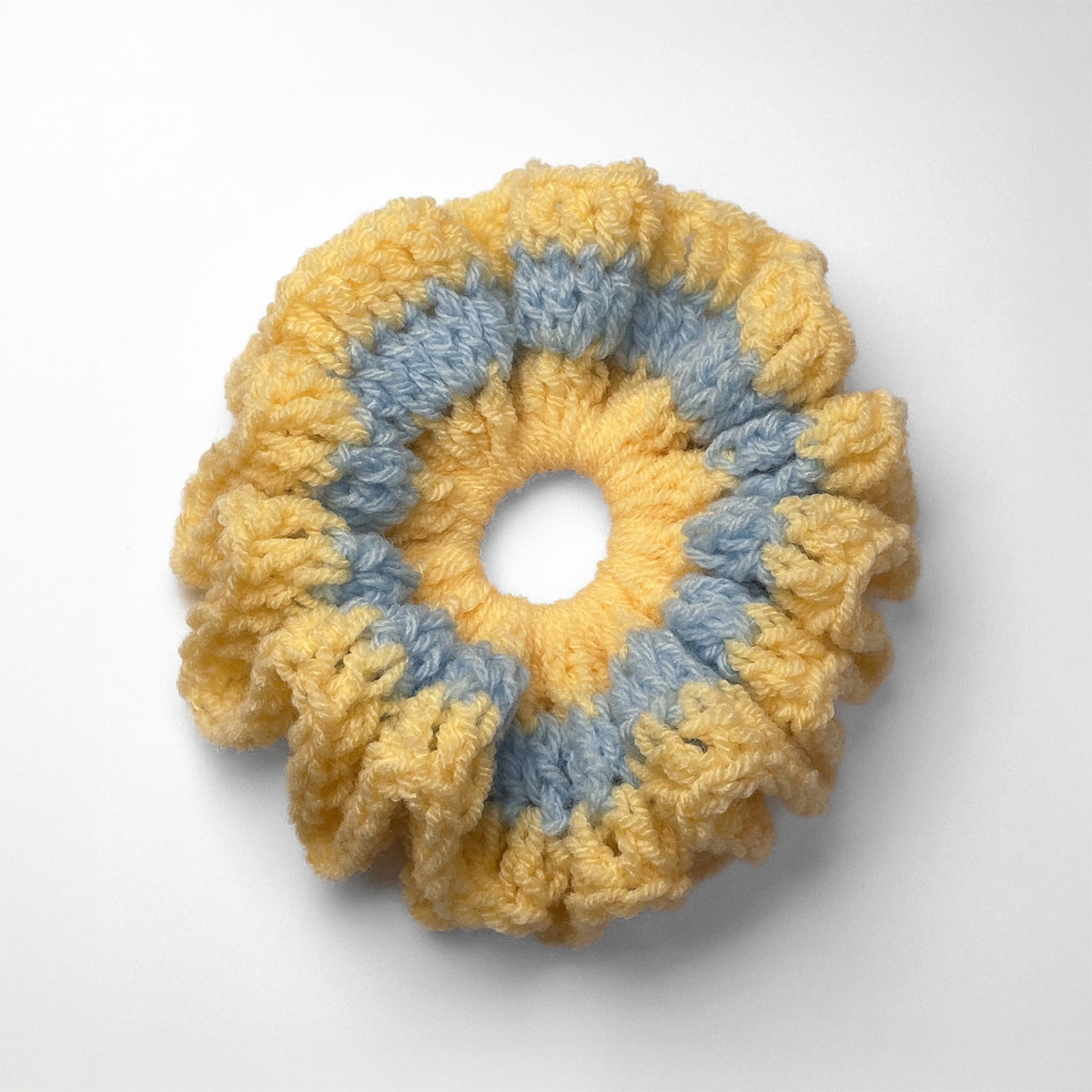 Ręcznie robiona gumka do włosów na szydełku wykonana z materiałów z upcyklingu, widok z góry na białym tle.