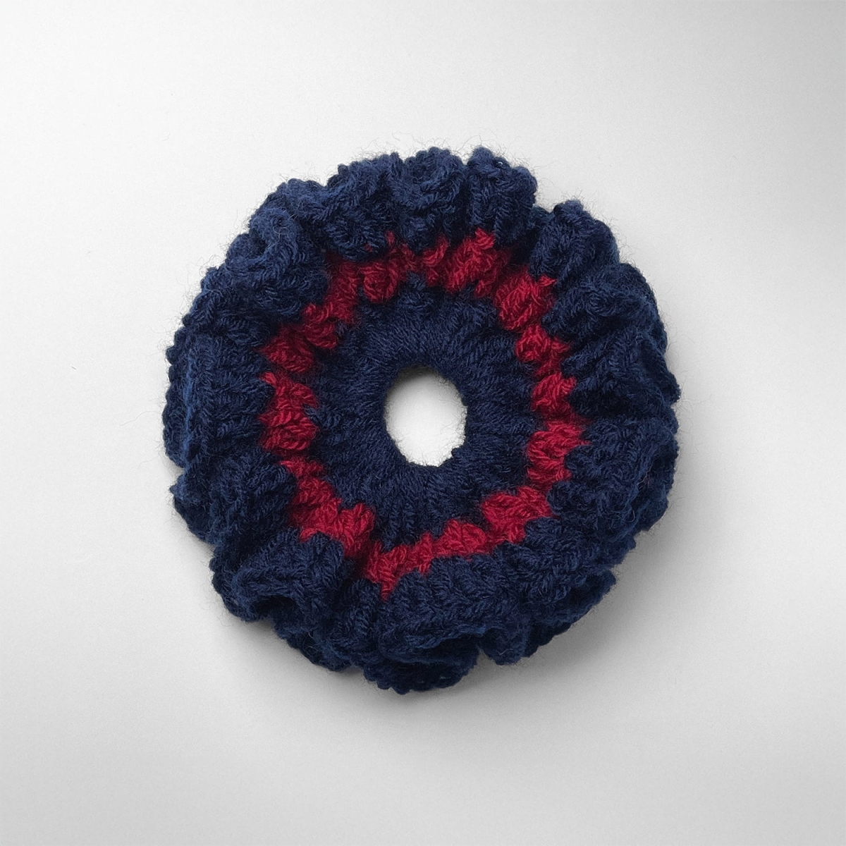 Ręcznie robiona gumka do włosów na szydełku wykonana z materiałów z upcyklingu, widok z góry na białym tle.