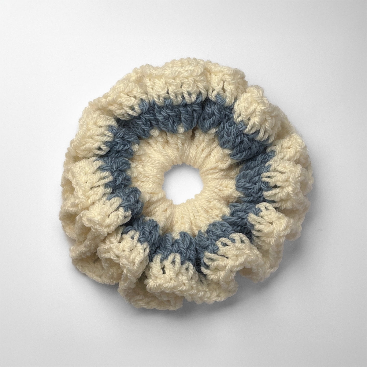 Ręcznie robiona gumka do włosów na szydełku wykonana z materiałów z upcyklingu, widok z góry na białym tle.