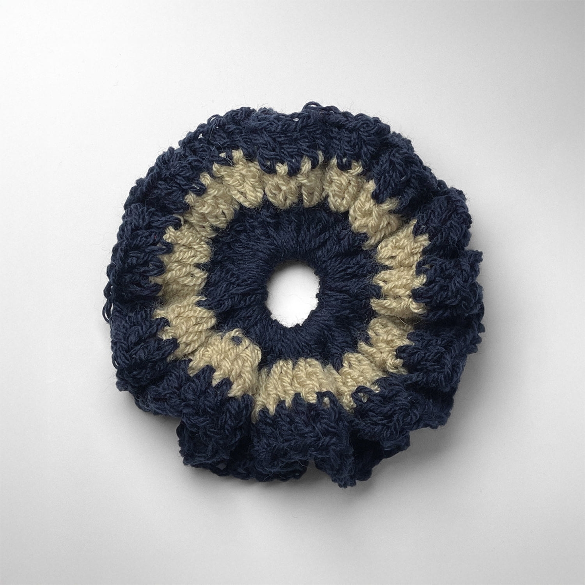 Ręcznie robiona gumka do włosów na szydełku wykonana z materiałów z upcyklingu, widok z góry na białym tle.