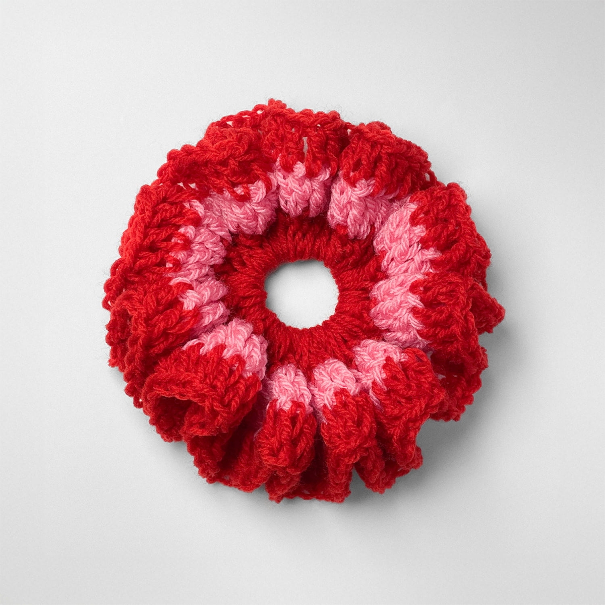 Ręcznie robiona gumka do włosów na szydełku wykonana z materiałów z upcyklingu, widok z góry na białym tle.