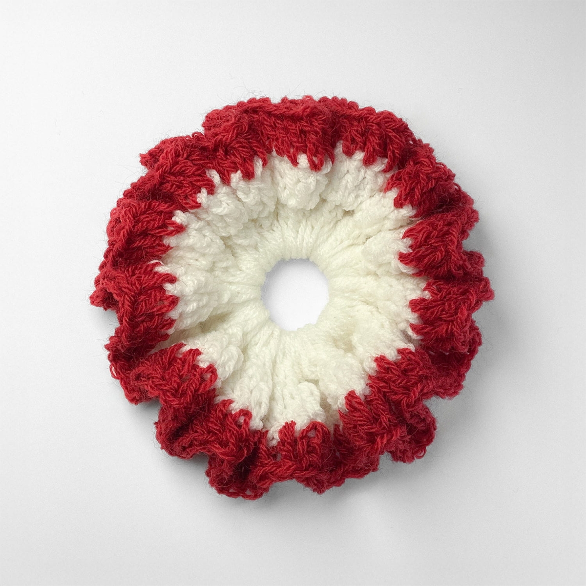 Ręcznie robiona gumka do włosów na szydełku wykonana z materiałów z upcyklingu, widok z góry na białym tle.