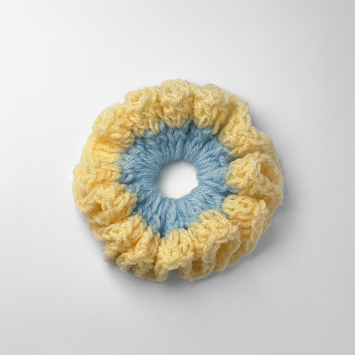 Ręcznie robiona gumka do włosów na szydełku wykonana z materiałów z upcyklingu, widok z góry na białym tle.