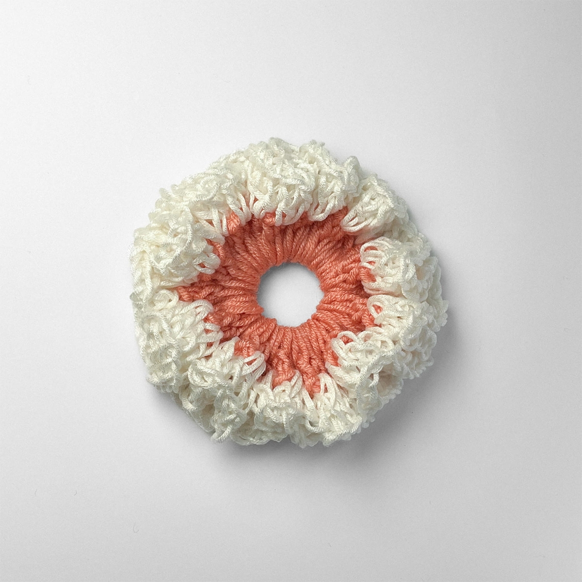 Ręcznie robiona gumka do włosów na szydełku wykonana z materiałów z upcyklingu, widok z góry na białym tle.