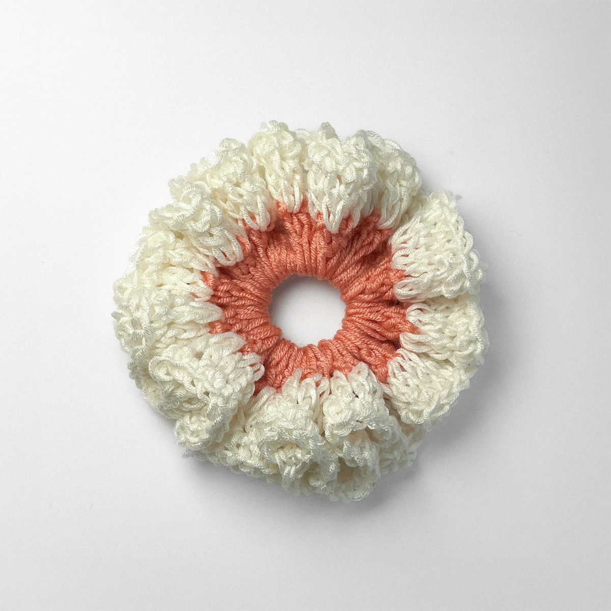 Ręcznie robiona gumka do włosów na szydełku wykonana z materiałów z upcyklingu, widok z góry na białym tle.