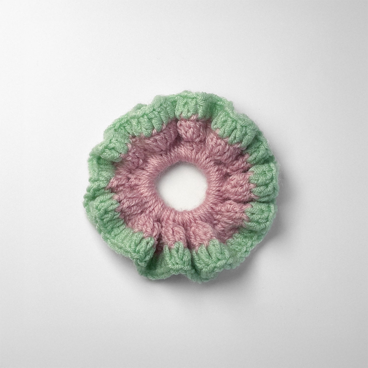 Ręcznie robiona gumka do włosów na szydełku wykonana z materiałów z upcyklingu, widok z góry na białym tle.