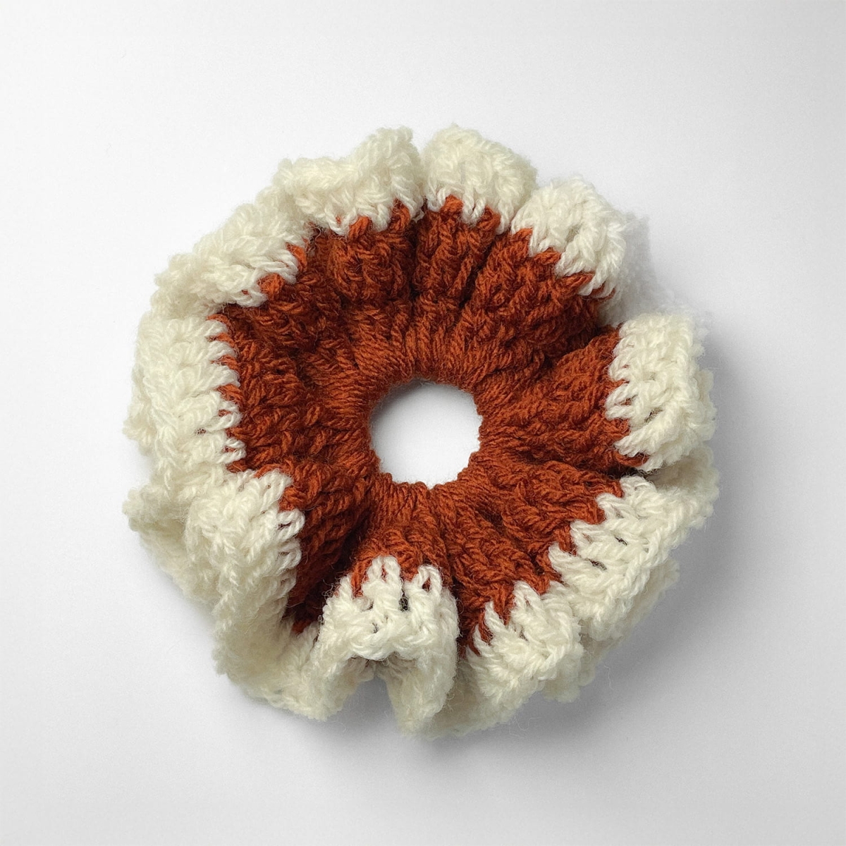 Ręcznie robiona gumka do włosów na szydełku wykonana z materiałów z upcyklingu, widok z góry na białym tle.