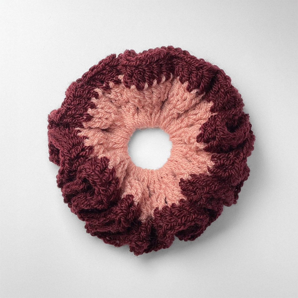 Ręcznie robiona gumka do włosów na szydełku wykonana z materiałów z upcyklingu, widok z góry na białym tle.