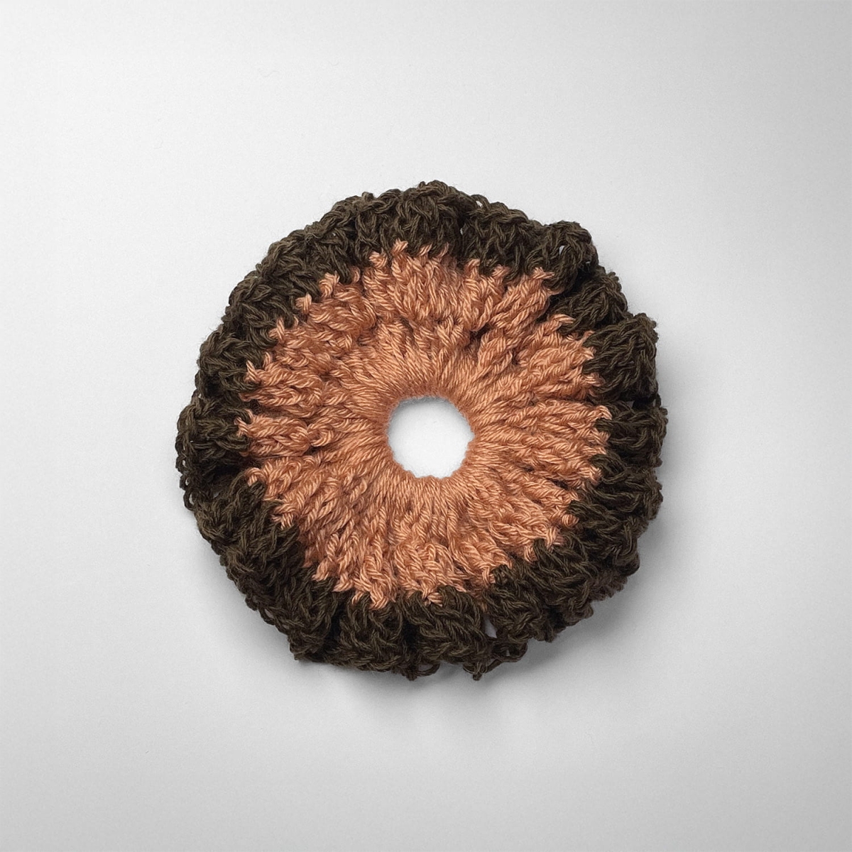 Ręcznie robiona gumka do włosów na szydełku wykonana z materiałów z upcyklingu, widok z góry na białym tle.