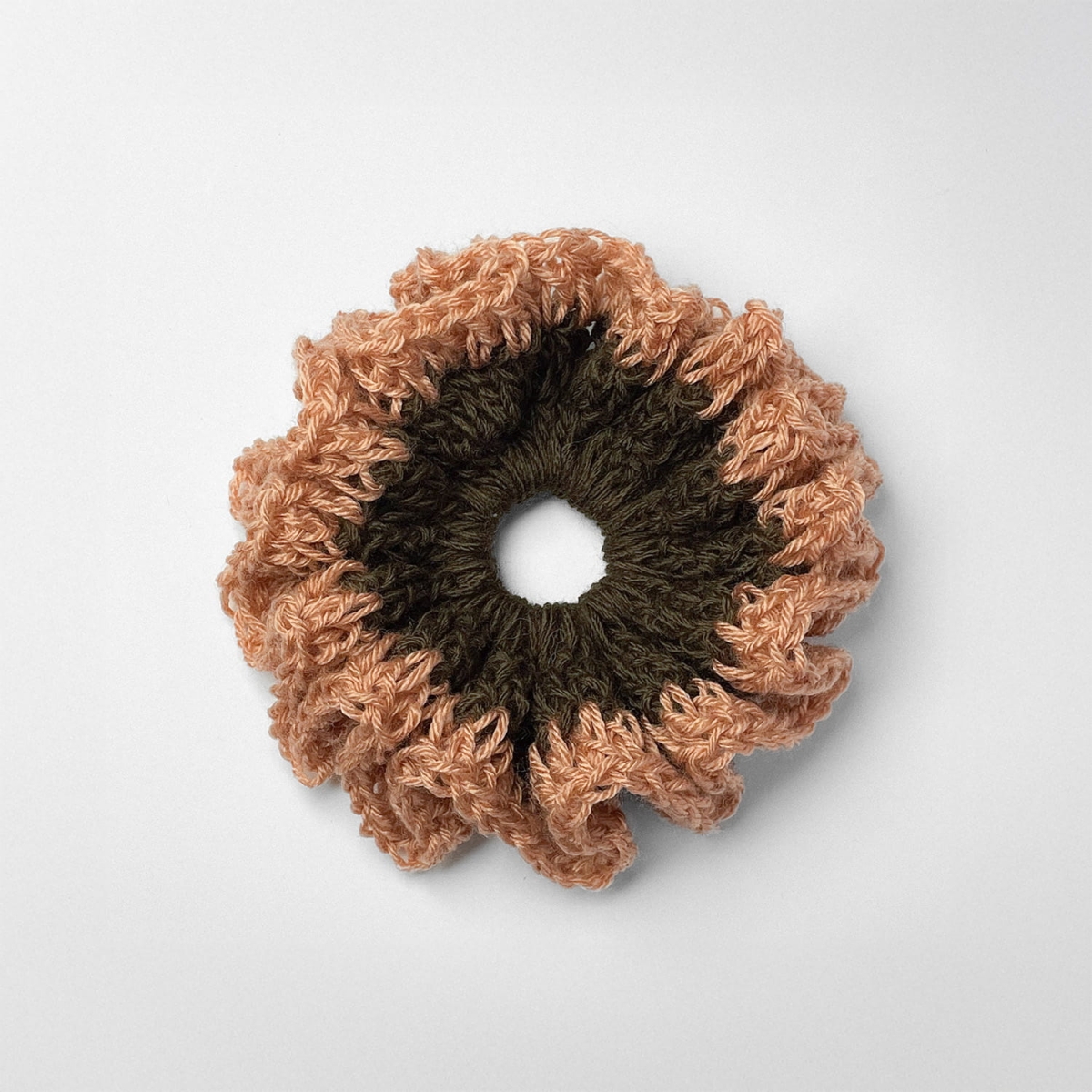 Ręcznie robiona gumka do włosów na szydełku wykonana z materiałów z upcyklingu, widok z góry na białym tle.