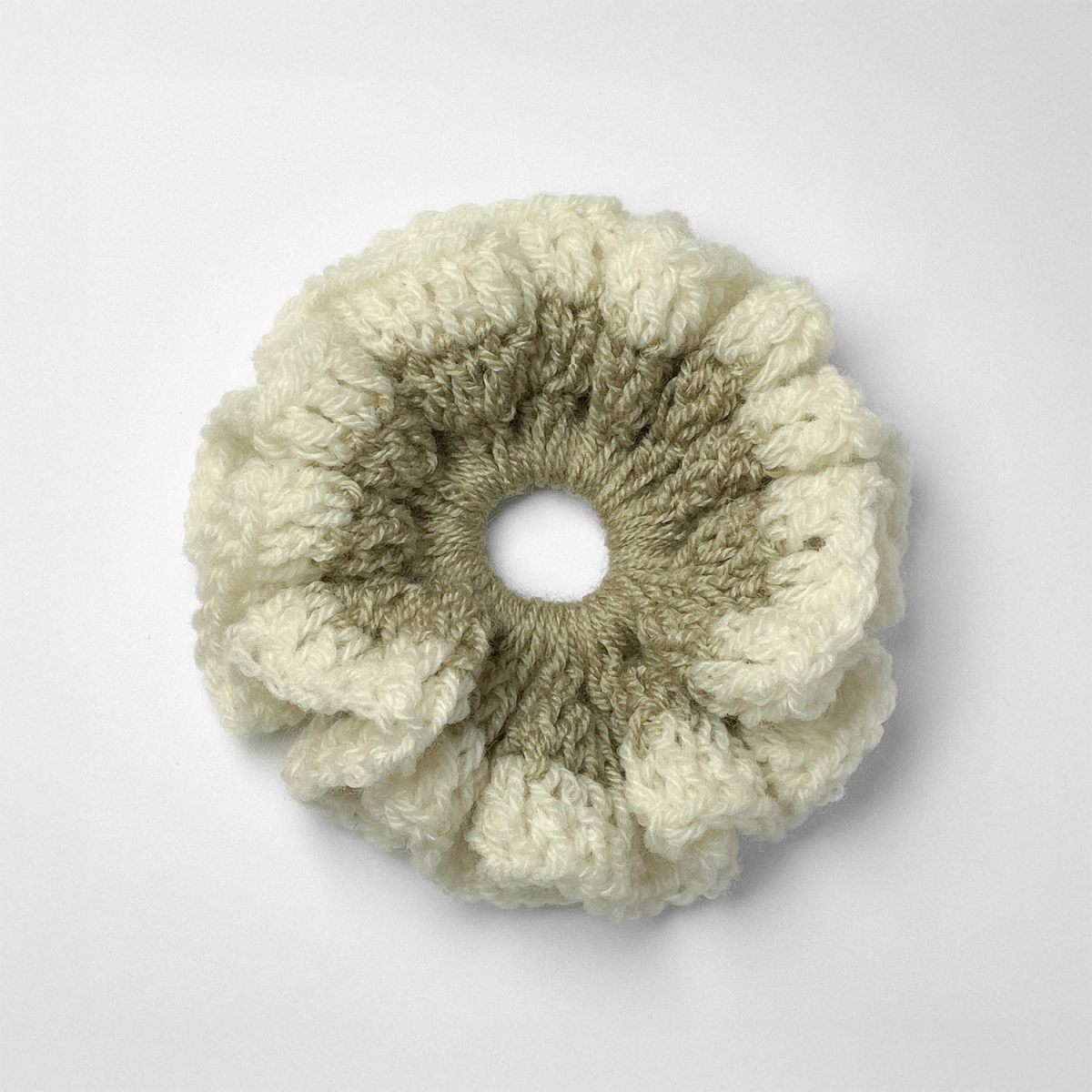 Ręcznie robiona gumka do włosów na szydełku wykonana z materiałów z upcyklingu, widok z góry na białym tle.