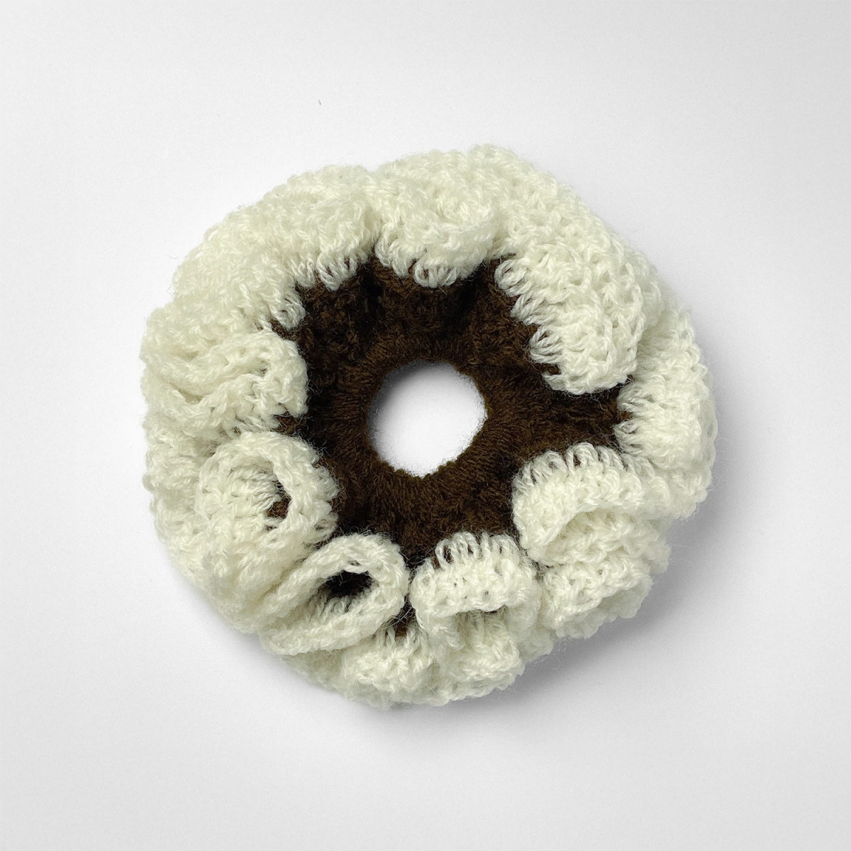 Ręcznie robiona gumka do włosów na szydełku wykonana z materiałów z upcyklingu, widok z góry na białym tle.