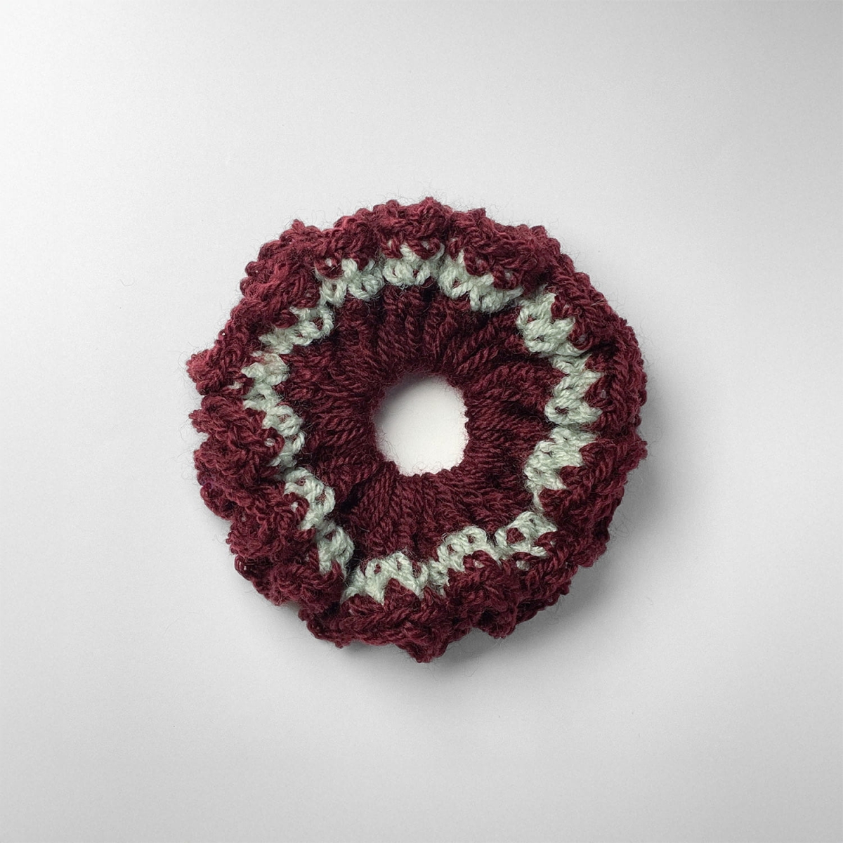 Ręcznie robiona gumka do włosów na szydełku wykonana z materiałów z upcyklingu, widok z góry na białym tle.