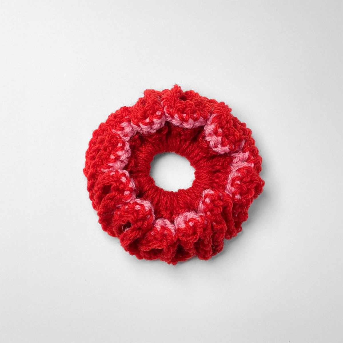 Ręcznie robiona gumka do włosów na szydełku wykonana z materiałów z upcyklingu, widok z góry na białym tle.