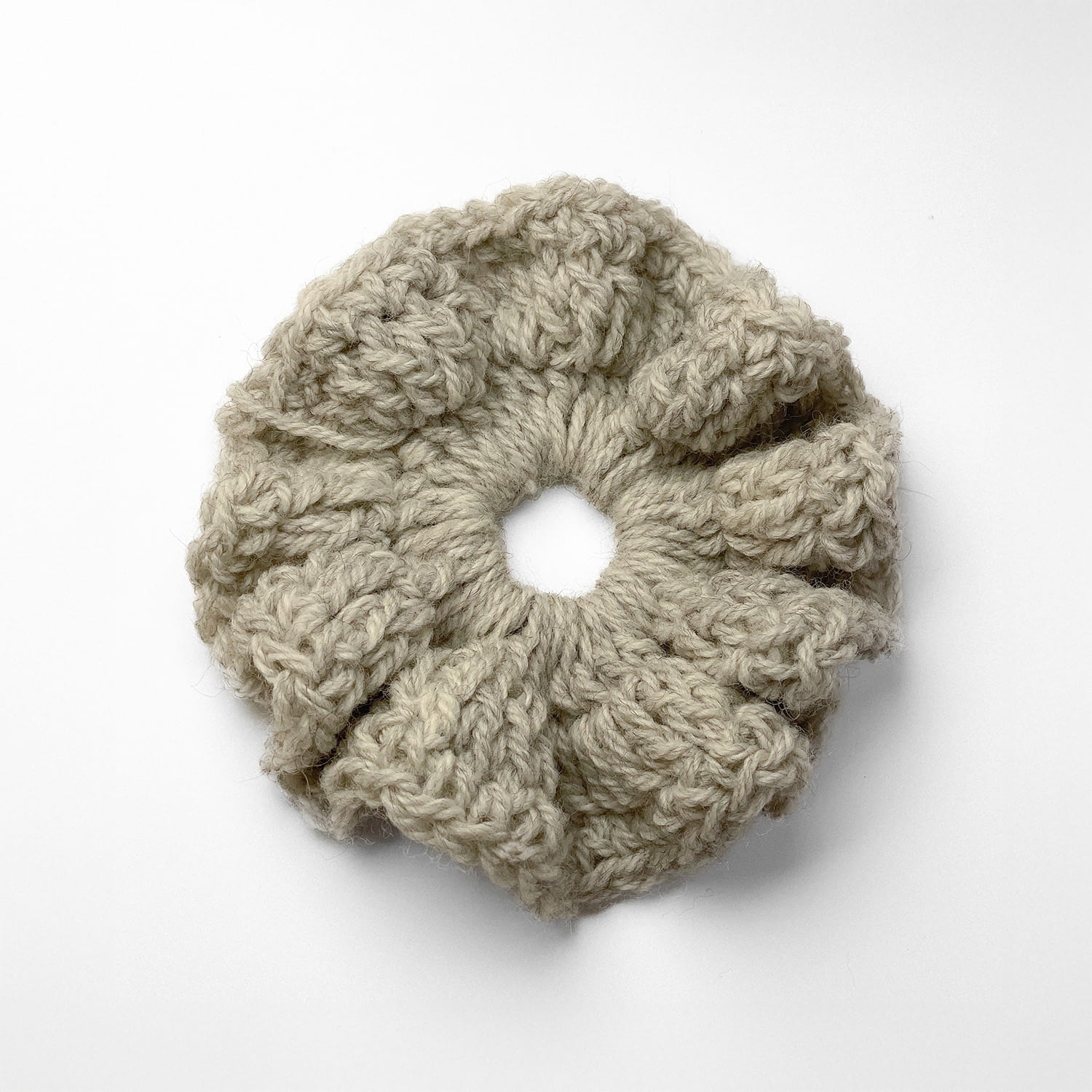 Ręcznie robiona gumka do włosów na szydełku wykonana z materiałów z upcyklingu, widok z góry na białym tle.