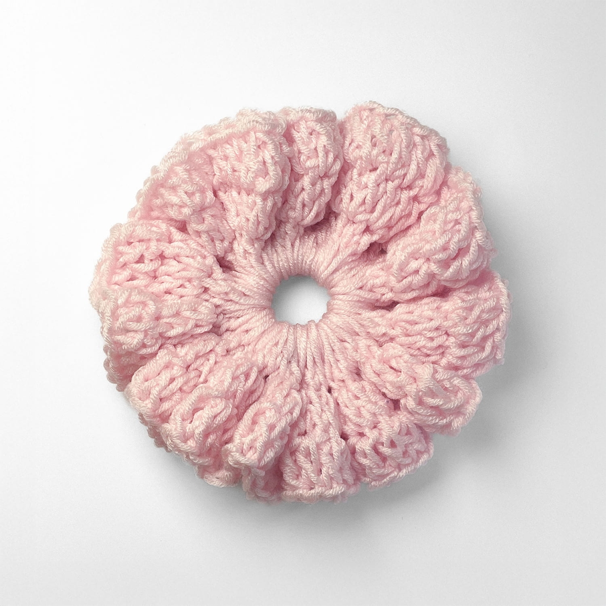 Ręcznie robiona gumka do włosów na szydełku wykonana z materiałów z upcyklingu, widok z góry na białym tle.