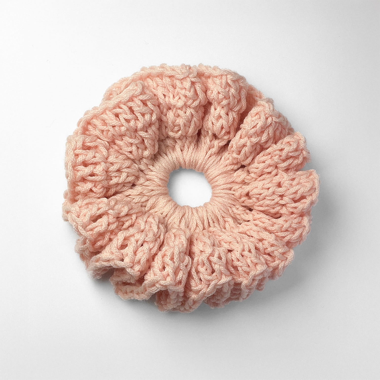 Ręcznie robiona gumka do włosów na szydełku wykonana z materiałów z upcyklingu, widok z góry na białym tle.