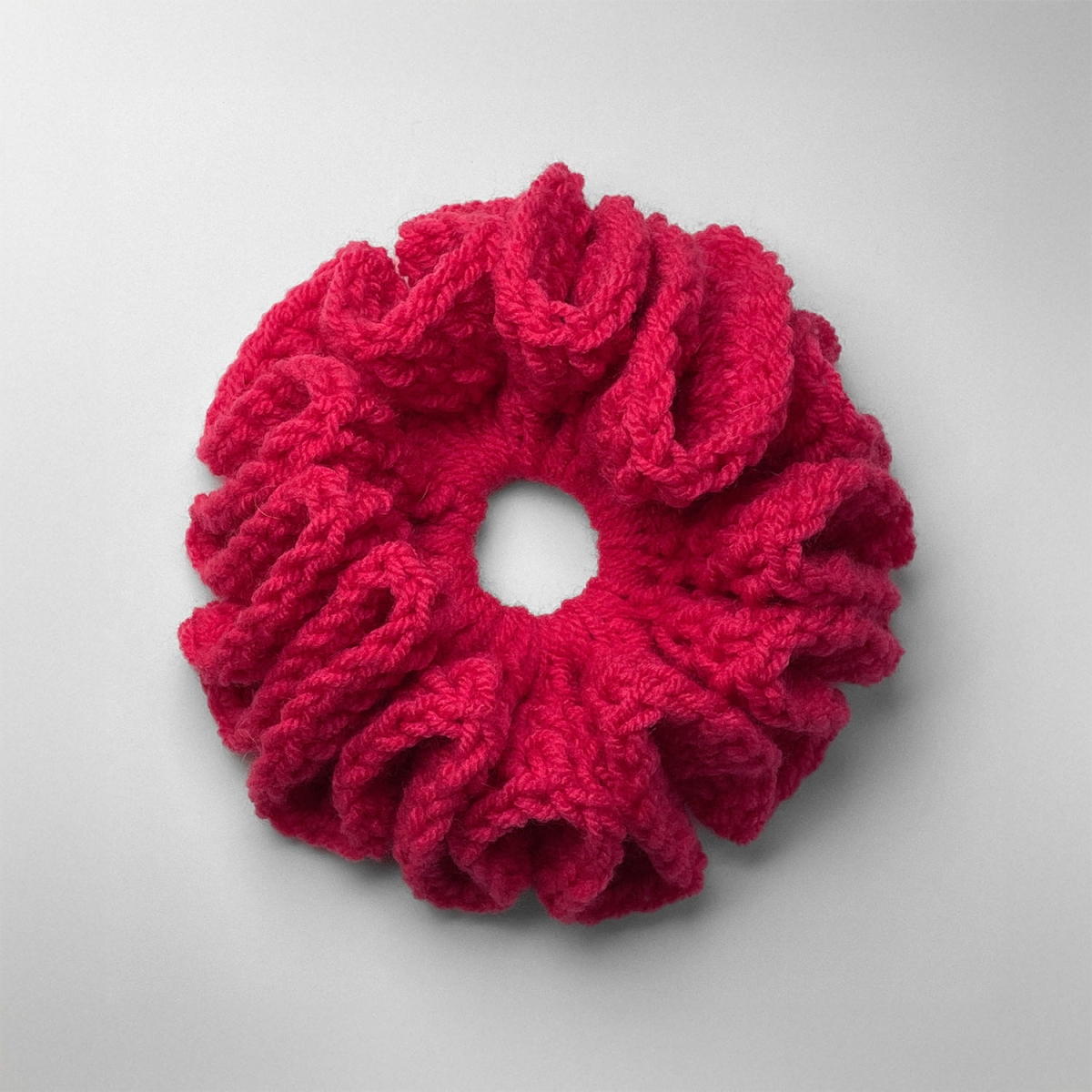 Ręcznie robiona gumka do włosów na szydełku wykonana z materiałów z upcyklingu, widok z góry na białym tle.