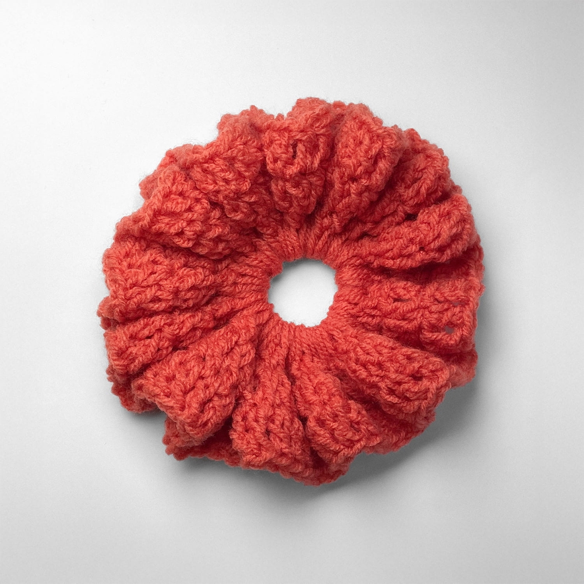 Ręcznie robiona gumka do włosów na szydełku wykonana z materiałów z upcyklingu, widok z góry na białym tle.