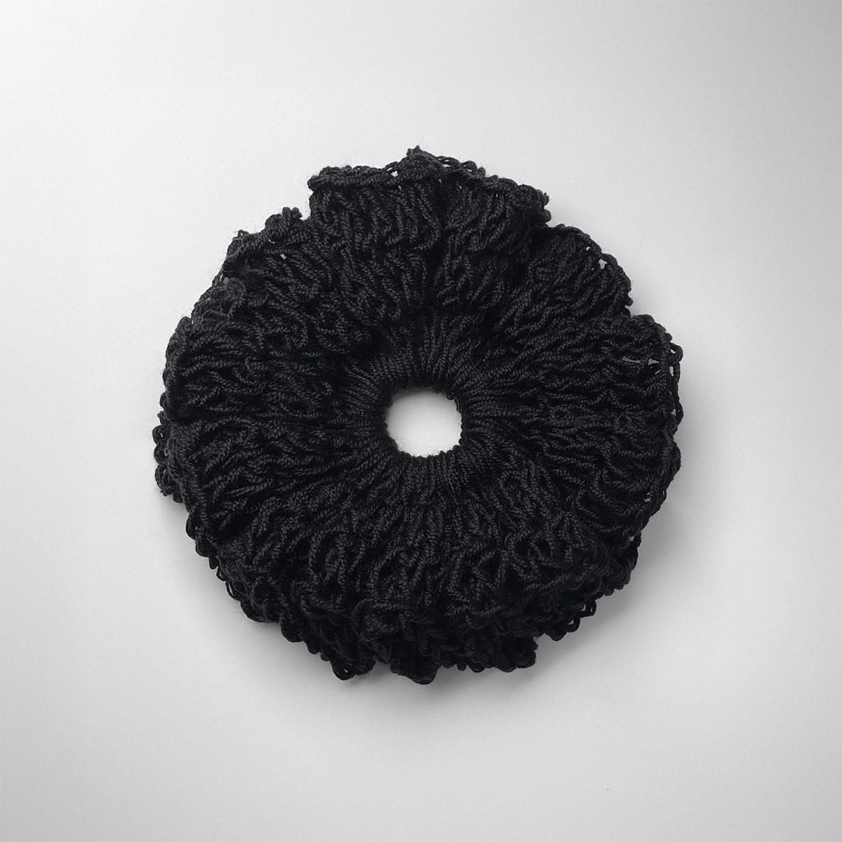 Ręcznie robiona gumka do włosów na szydełku wykonana z materiałów z upcyklingu, widok z góry na białym tle.