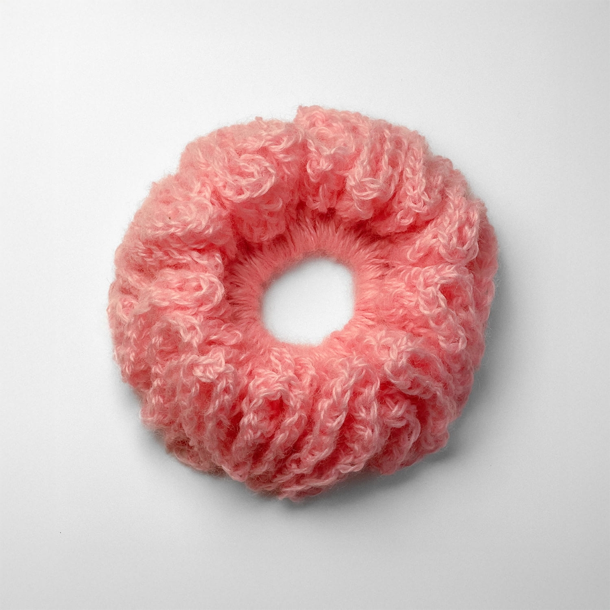 Ręcznie robiona gumka do włosów na szydełku wykonana z materiałów z upcyklingu, widok z góry na białym tle.