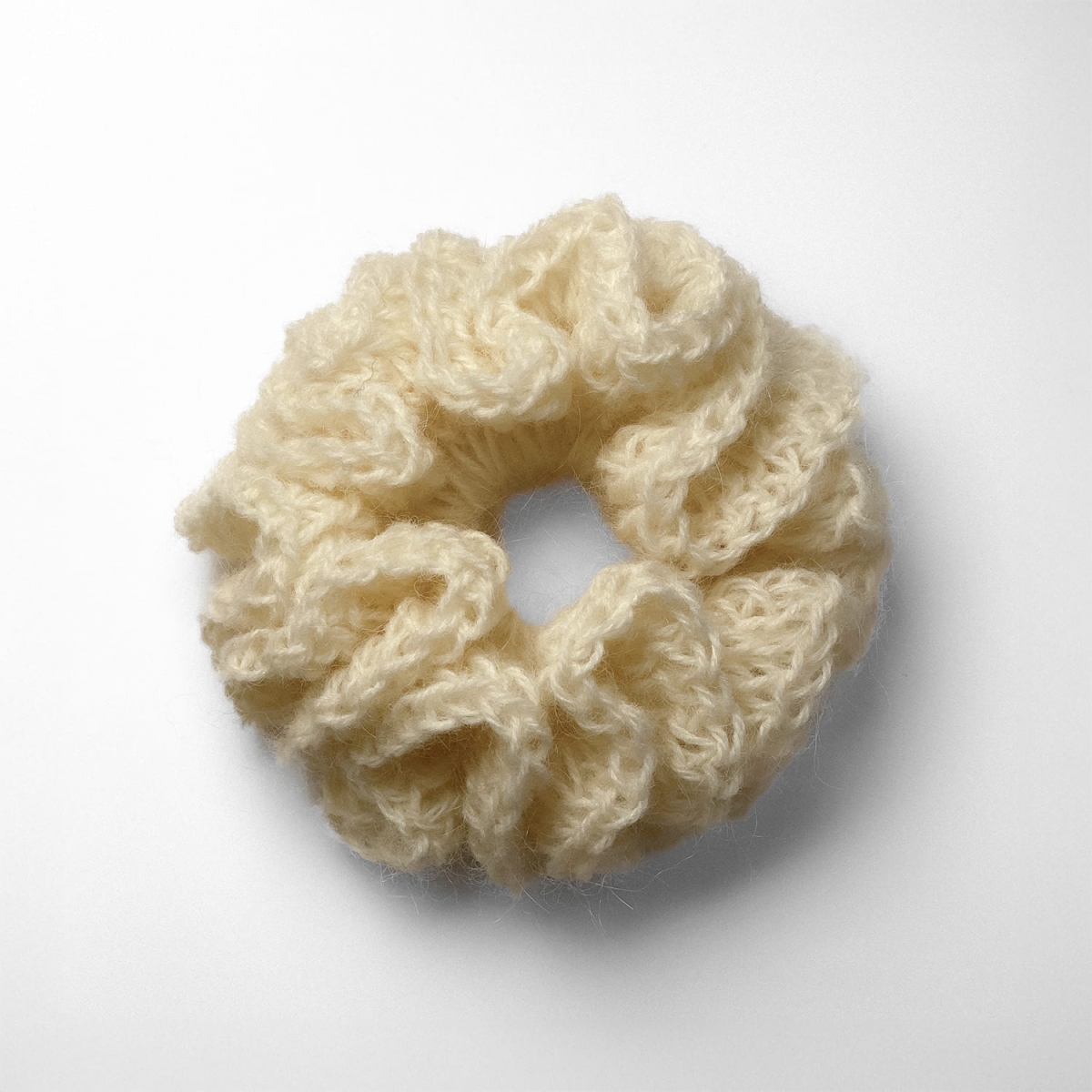 Ręcznie robiona gumka do włosów na szydełku wykonana z materiałów z upcyklingu, widok z góry na białym tle.