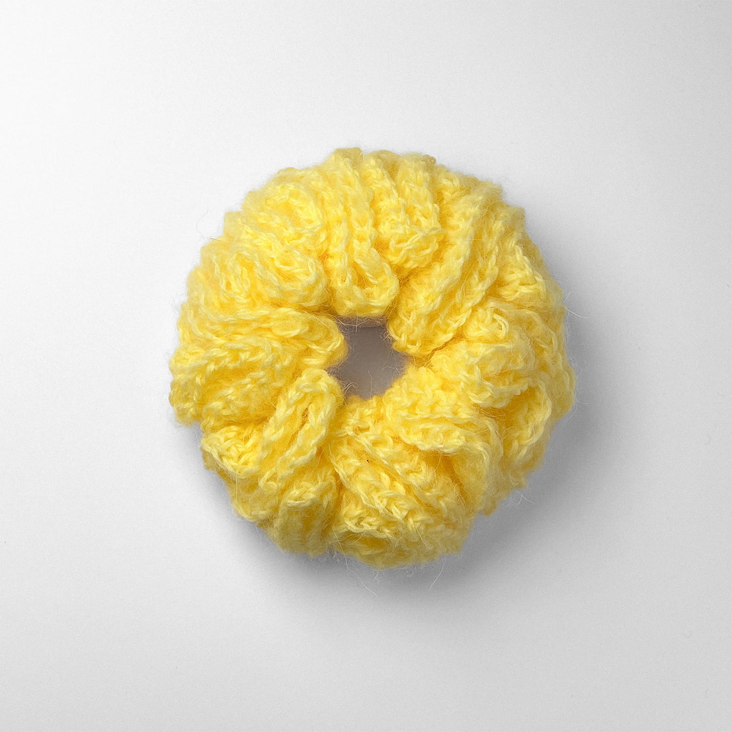 Ręcznie robiona gumka do włosów na szydełku wykonana z materiałów z upcyklingu, widok z góry na białym tle.
